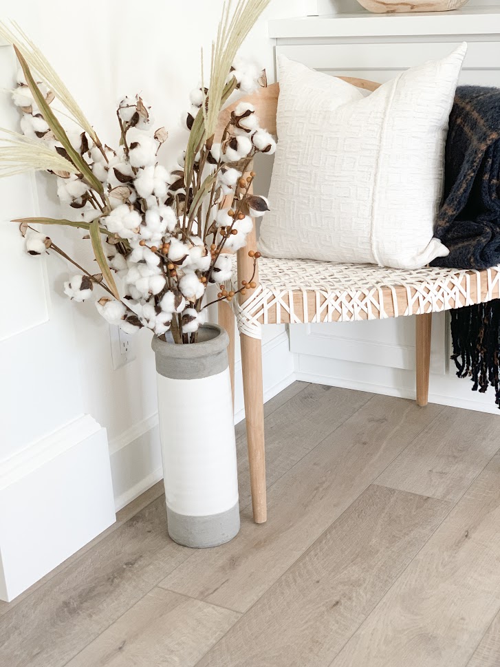 chair with cotton stem spray in vase next to it